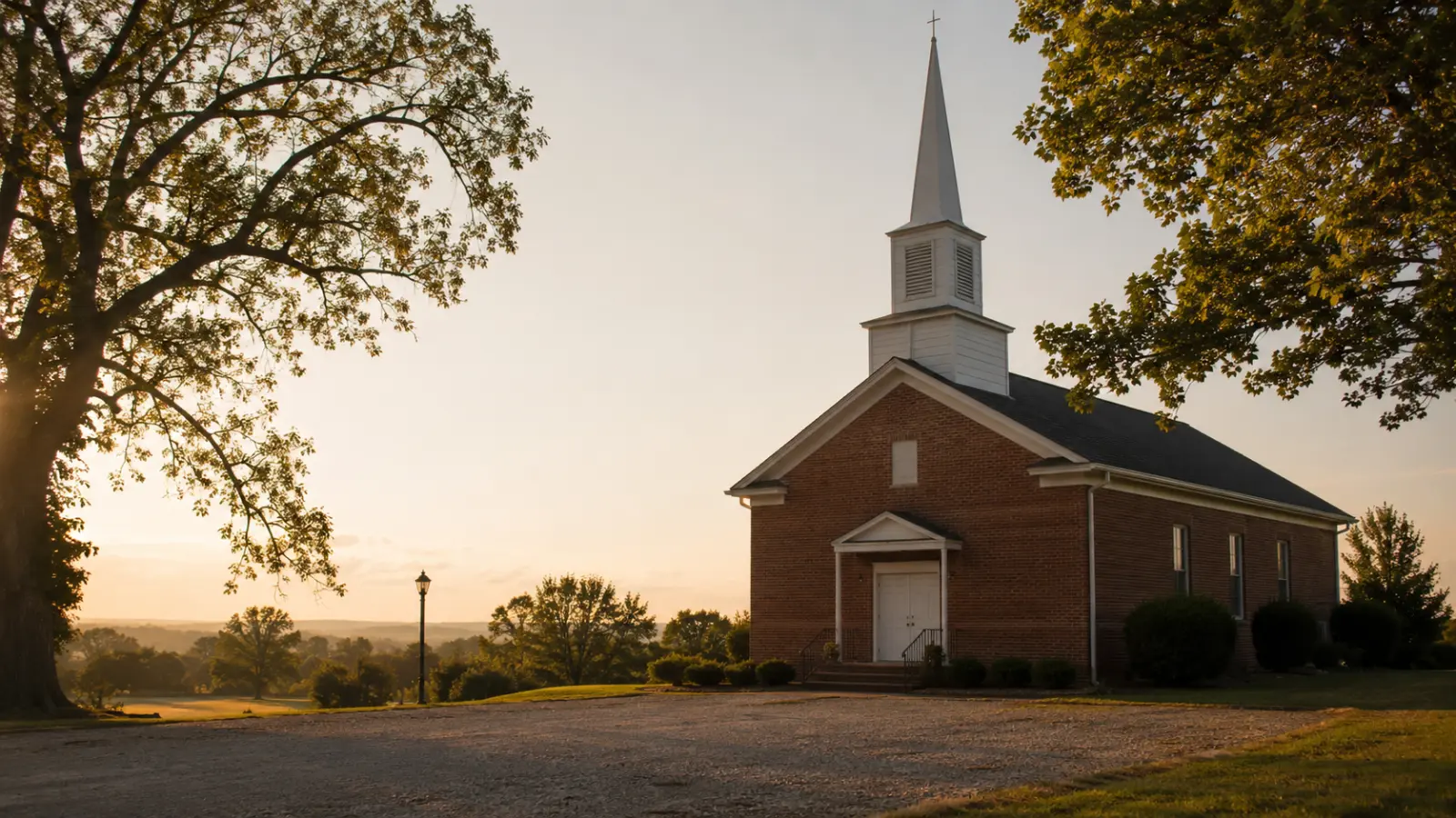 A country Church of Christ building with its steeple lit by golden-hour sunlight
